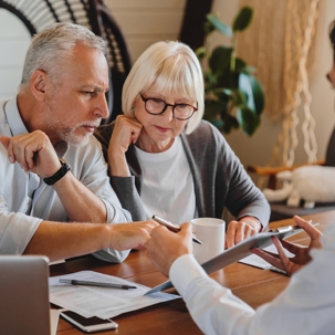 Older couple attentively reviewing documents with a lawyer